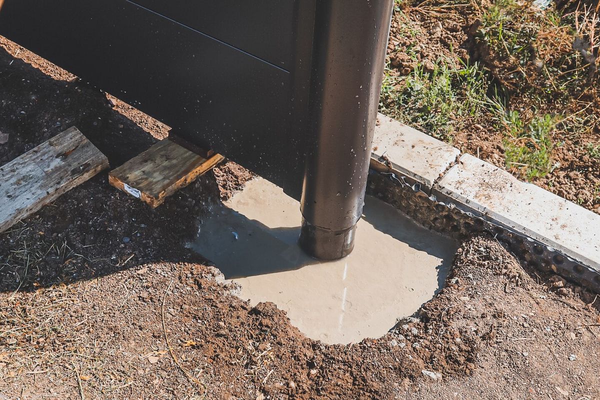 Der Schnellbeton wird in die Fundamentlöcher gegossen und härtet in wenigen Stunden aus